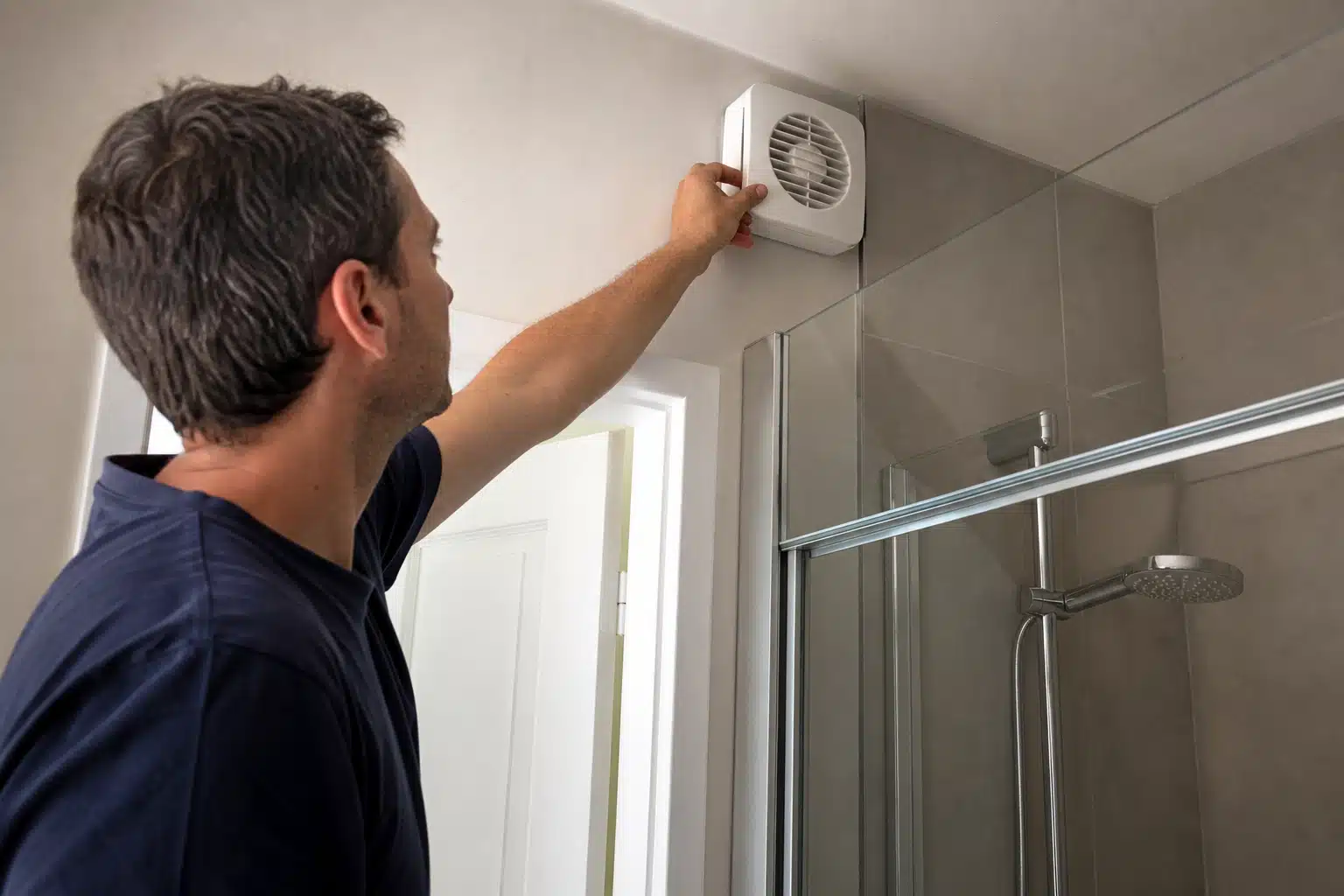 Homme retirant un ventilateur d'extraction au plafond